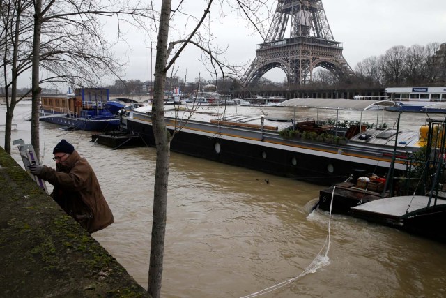 A man climbs a ladder after he used a small boat to make his way from a houseboat as the Seine River overflows its banks as heavy rains throughout the country have caused flooding, in Paris, France, January 26, 2018. REUTERS/Pascal Rossignol