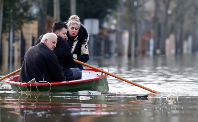 Residents on a small boat leave home in a flooded street of Villeneuve-Saint-Georges, near Paris, France January 26, 2018. REUTERS/Christian Hartmann