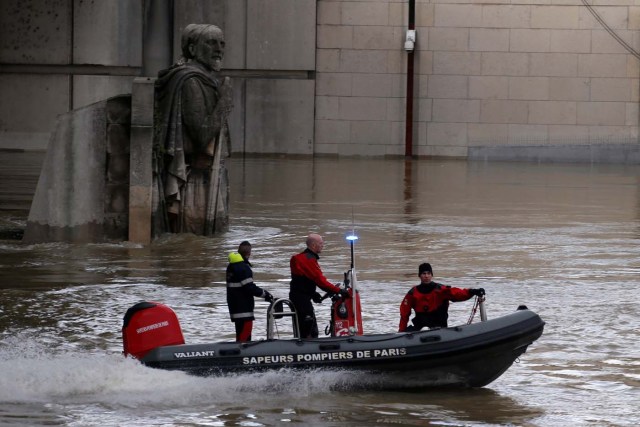 Members of the Paris fire brigade navigate a small craft past the Zouave soldier statue under the Pont d'Alma as the Seine River overflows its banks as heavy rains throughout the country have caused flooding, in Paris, France, January 26, 2018. REUTERS/Pascal Rossignol?