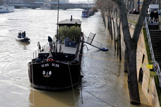 Paris police navigate near a houseboat on the Seine River that overflowed its banks as heavy rains throughout the country have caused flooding, in Paris, France, January 26, 2018. REUTERS/Pascal Rossignol?