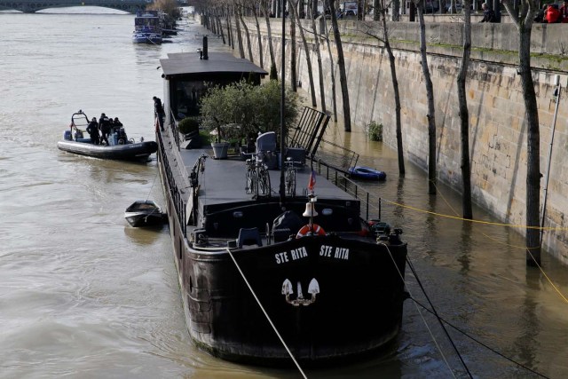 Paris police navigate near a houseboat on the Seine River that overflowed its banks as heavy rains throughout the country have caused flooding, in Paris, France, January 26, 2018. REUTERS/Pascal Rossignol