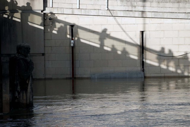 Shadows are cast on a wall as people stop on a bridge to look at the Zouave soldier statue under the Pont d'Alma as the Seine River overflows its banks as heavy rains throughout the country have caused flooding, in Paris, France, January 26, 2018. REUTERS/Pascal Rossignol