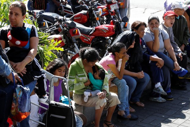 Una mujer amamanta a un niño mientras espera en una cola para comprar comida, en una acera frente a un supermercado en Caracas, Venezuela, el 6 de enero de 2018. REUTERS / Marco Bello