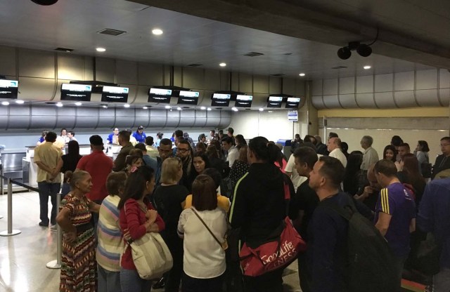 People queue at counters of Panama's Copa Airlines at Caracas' international airport on April 6, 2018 after Venezuela suspended the company's flights in an escalating diplomatic row. Panama on April 5 ordered Venezuela's ambassador out and recalled its own envoy to the country as Caracas imposed sanctions on senior Panamanian officials and suspended flights in an escalating diplomatic row. At issue is Panama's alignment with other Latin American countries as well as the European Union, Canada and the United States that have taken measures against President Nicolas Maduro's and his government on the grounds that he is undemocratically tightening his hold on power. / AFP PHOTO / Federico PARRA