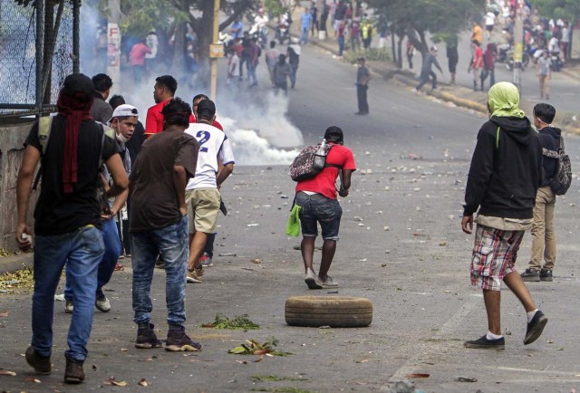 Students clash with riot police agents close to Nicaragua's Technical College during a protest against government's reforms in the Institute of Social Security (INSS) in Managua on April 21, 2018. A protester and a policeman were killed in the Nicaraguan capital Managua after demonstrations over pension reform turned violent Thursday night, officials said. The deaths came after protests by both opponents and supporters of a new law, which increases employer and employee contributions while reducing the overall amount of pensions by five percent, rocked the capital for a second day. / AFP PHOTO / INTI OCON