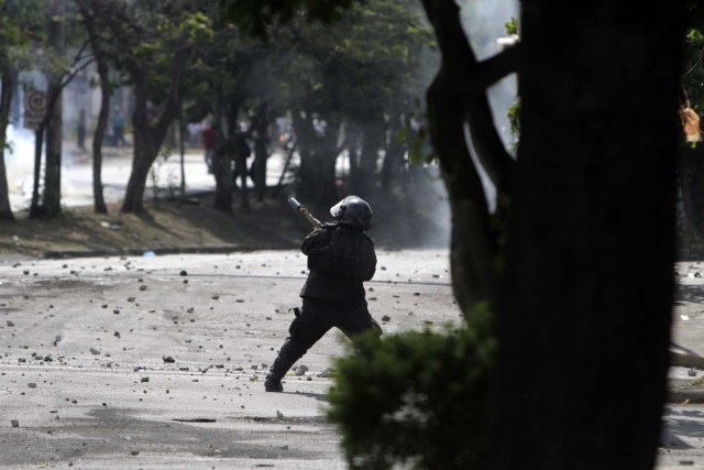 A riot police agent shoots a tear gas canister to students during protests against government's reforms in the Institute of Social Security (INSS) in Managua on April 21, 2018. Violent protests against a proposed change to Nicaragua's pension system have left at least 10 people dead over two days, the government said Friday. In the biggest protests in President Daniel Ortega's 11 years in office in this poor Central American country, people are angry over the plan because workers and employers would have to chip in more toward the retirement system. / AFP PHOTO / INTI OCON