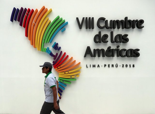 Un hombre pasa junto a un logotipo oficial de la VIII Cumbre de las Américas en el centro de convenciones de Lima, Perú, el 14 de abril de 2018. REUTERS / Marcos Brindicci