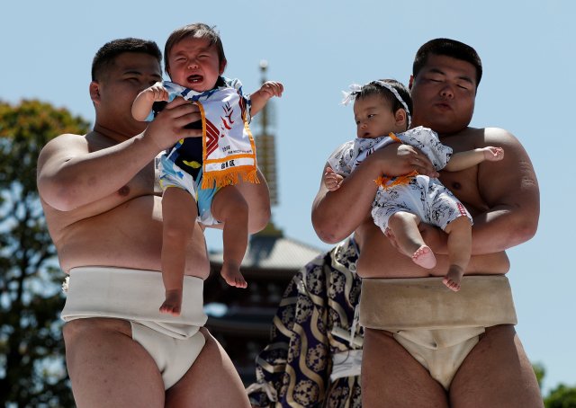 Babies cry as they are held up by amateur sumo wrestlers during a baby crying contest at Sensoji temple in Tokyo, Japan, April 28, 2018. In the contest two wrestlers each hold a baby while a referee makes faces and loud noises to make them cry. The baby who cries the loudest wins. The ritual is believed to aid the healthy growth of the children and ward off evil spirits. 160 children took part in the event in this year, the organiser said. REUTERS/Issei Kato