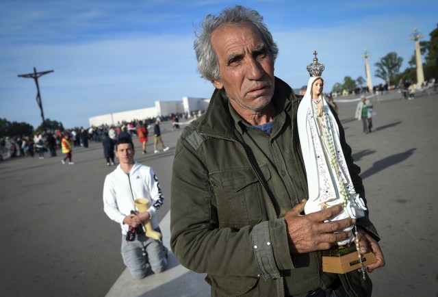 Un peregrino lleva una estatua de Nuestra Señora de Fátima cuando llega al santuario de Fátima el 13 de mayo de 2018. Miles de peregrinos se reunieron en el Santuario de Fátima para celebrar el aniversario del milagro de Fátima cuando tres niños pastores afirmaron haber visto a la Virgen María en mayo de 1917. / AFP PHOTO / MIGUEL RIOPA