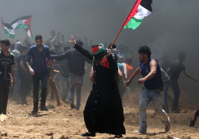 Una mujer palestina agita su bandera nacional durante los enfrentamientos con las fuerzas israelíes cerca de la frontera entre Israel y la Franja de Gaza, al este de Jabalia el 14 de mayo de 2018, mientras los palestinos protestan por la inauguración de la embajada de Estados Unidos tras su controvertido traslado a Jerusalén. / AFP PHOTO / MOHAMMED ABED