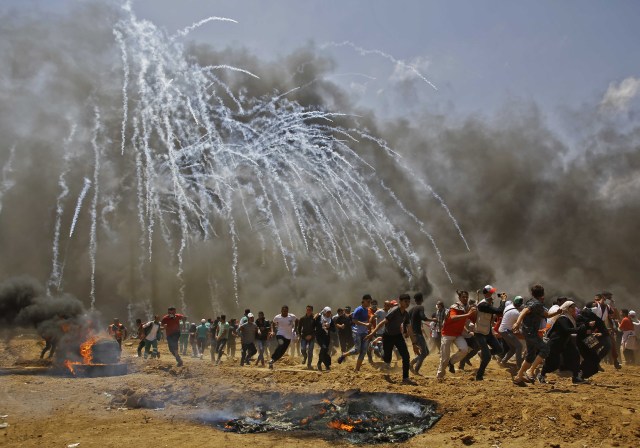 Los palestinos huyen del gas lacrimógeno durante los enfrentamientos con las fuerzas de seguridad israelíes cerca de la frontera entre Israel y la Franja de Gaza, al este de Jabalia el 14 de mayo de 2018, mientras los palestinos protestan por la inauguración de la embajada de Estados Unidos tras su controvertido traslado a Jerusalén. / AFP PHOTO / MOHAMMED ABED