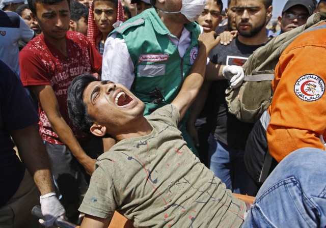 Los servicios de emergencia y los palestinos llevan a un manifestante herido durante los enfrentamientos con las fuerzas de seguridad israelíes cerca de la frontera entre Israel y la Franja de Gaza, al este de Jabalia, el 14 de mayo de 2018, mientras los palestinos protestan por la inauguración de la embajada de Estados Unidos tras su controvertido traslado a Jerusalén. / AFP PHOTO / MOHAMMED ABED 