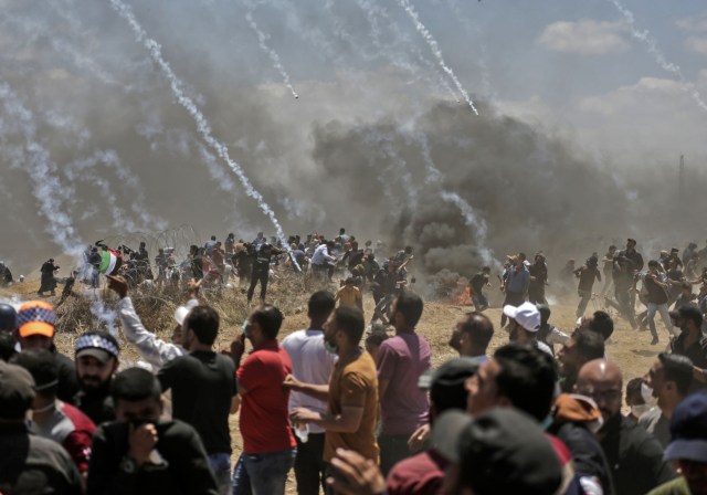 Los palestinos huyen del gas lacrimógeno durante los enfrentamientos con fuerzas israelíes cerca de la frontera entre Gaza e Israel al este de la ciudad de Gaza el 14 de mayo de 2018, mientras los palestinos protestan por la inauguración de la embajada de Estados Unidos tras su controvertido traslado a Jerusalén. Docenas de palestinos fueron asesinados por disparos israelíes el 14 de mayo cuando decenas de miles protestaron y estallaron enfrentamientos a lo largo de la frontera de Gaza contra la transferencia de su embajada a Jerusalén, luego de meses de protestas globales, ira palestina y elogios exuberantes de los israelíes por el presidente Donald Trump decisión dejando de lado décadas de precedentes. / AFP PHOTO / MAHMUD HAMS