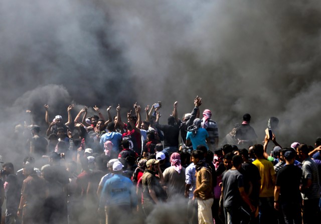 Los palestinos gritan consignas durante los enfrentamientos con las fuerzas de seguridad israelíes cerca de la frontera entre Gaza e Israel al este de la ciudad de Gaza el 14 de mayo de 2018, mientras los palestinos protestan por la inauguración de la embajada de Estados Unidos tras su controvertido traslado a Jerusalén. Docenas de palestinos fueron asesinados por disparos israelíes el 14 de mayo cuando decenas de miles protestaron y estallaron enfrentamientos a lo largo de la frontera de Gaza contra la transferencia de su embajada a Jerusalén, luego de meses de protestas globales, ira palestina y elogios exuberantes de los israelíes por el presidente Donald Trump decisión dejando de lado décadas de precedentes. / AFP PHOTO / MAHMUD HAMS