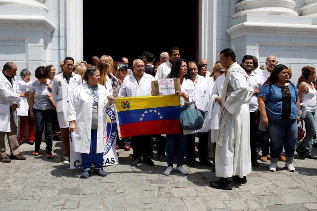 Los venezolanos, incluidos los médicos, sostienen pancartas que dicen "Solidaridad" mientras se reúnen fuera de un hospital público de niños durante un apagón en Caracas, Venezuela, 10 de marzo de 2019. REUTERS / Marco Bello